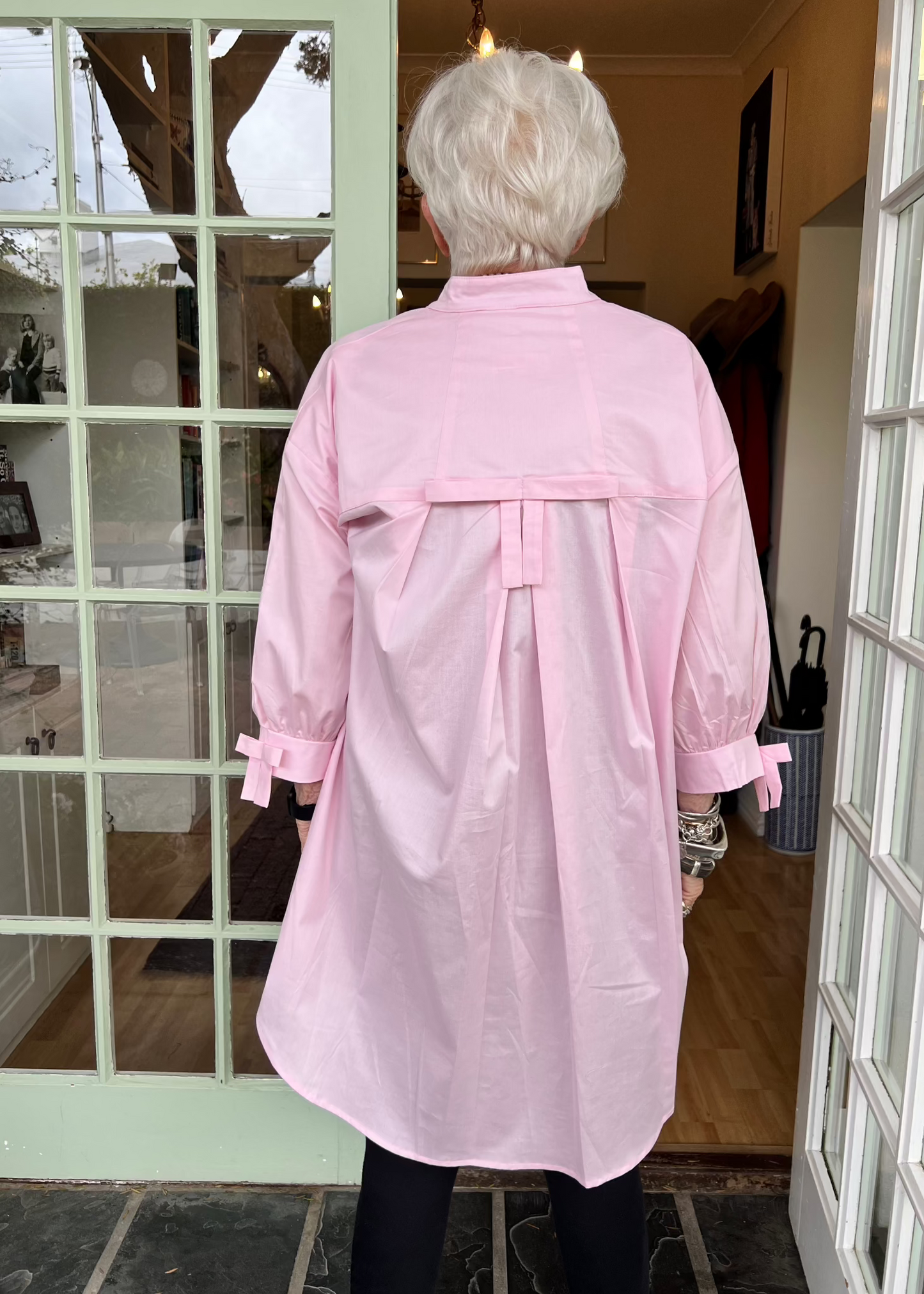 100% crisp cotton poplin women's shirt featuring dramatic back pleat with tied bow and decorative bow cuffs.