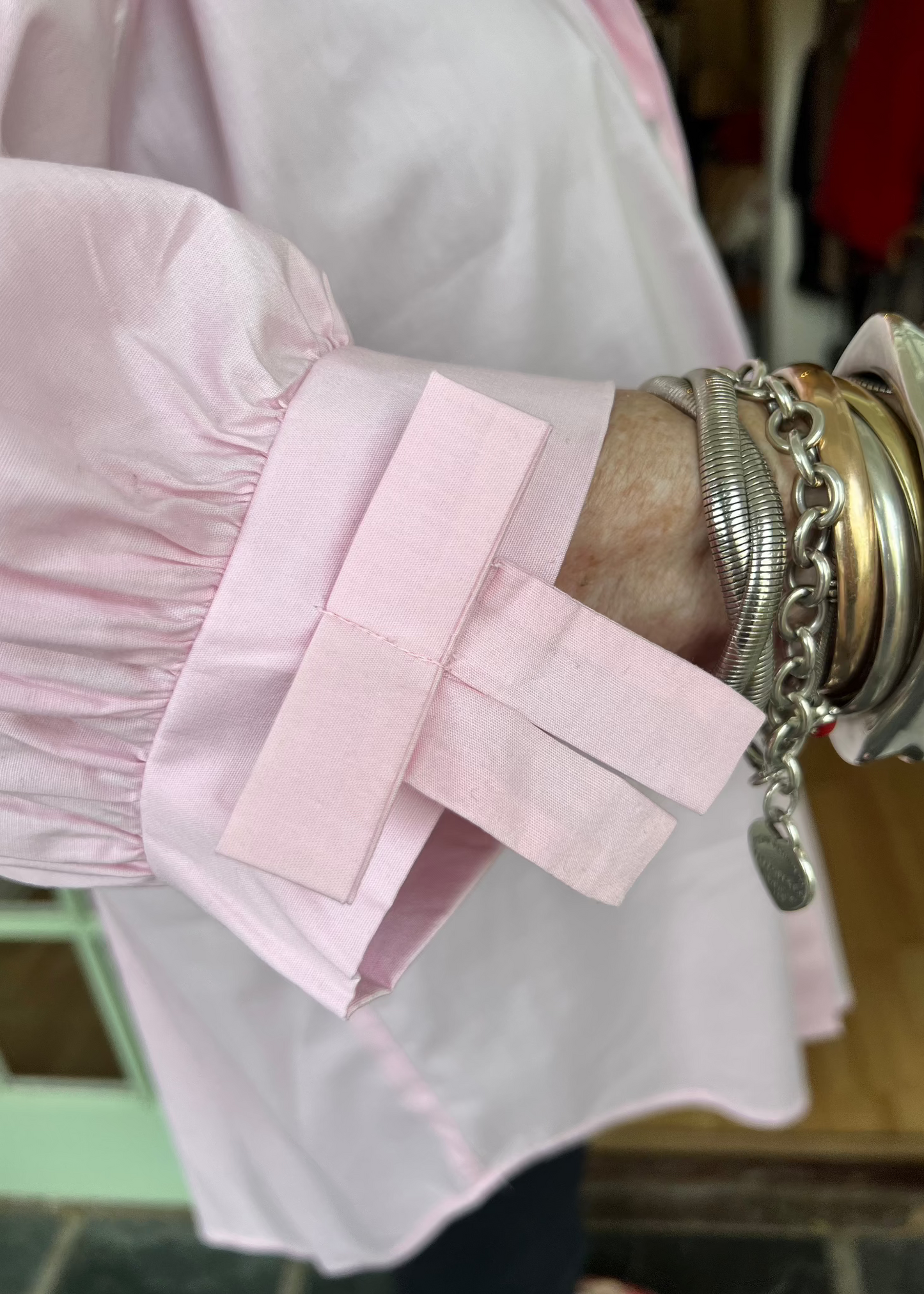 100% crisp cotton poplin women's shirt featuring dramatic back pleat with tied bow and decorative bow cuffs.