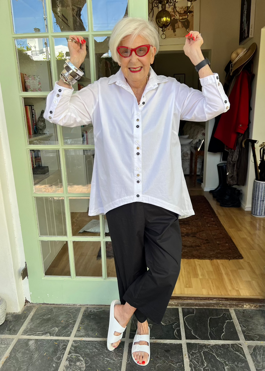 With its cheerful lineup of 26 buttons in three contrasting colours, this crisp cotton shirt brings a touch of whimsy to your everyday wardrobe. Designed with thoughtful asymmetry, it sits slightly shorter at the front and longer at the back - a clever detail that makes it the perfect partner for our Wide-Legged Pants.