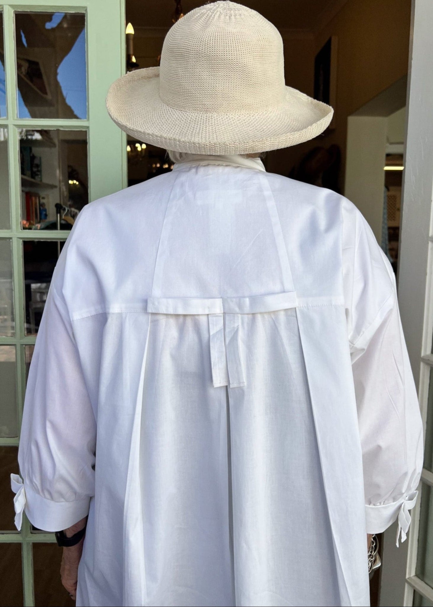 100% crisp cotton poplin women's shirt featuring dramatic back pleat with tied bow and decorative bow cuffs.