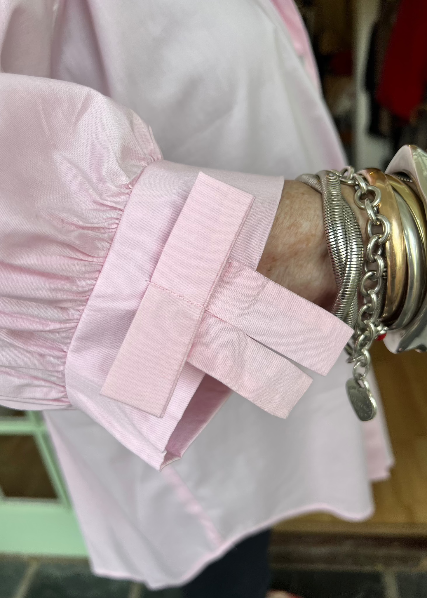 100% crisp cotton poplin women's shirt featuring dramatic back pleat with tied bow and decorative bow cuffs.
